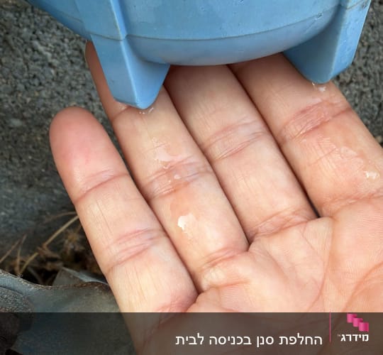 יד מחזיקה מתחת למתקן מים כחול